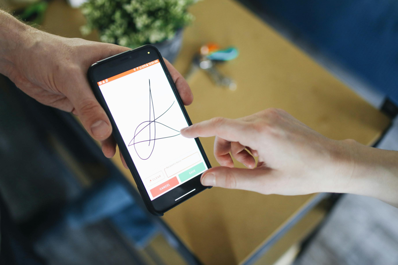 photo of someone signing on a mobile device using their finger